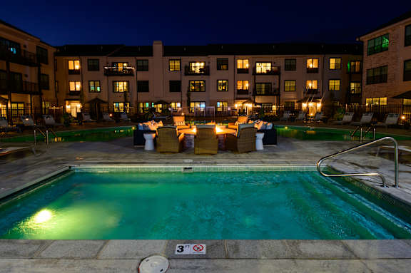 A swimming pool at night with a building in the background.