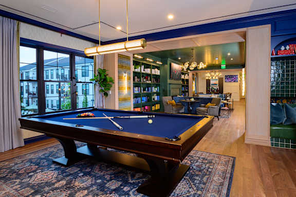 A pool table in a room with a view of the pool deck