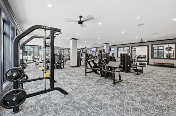 A gym with a variety of equipment including a weight machine and a squat rack. at Maison Apartments, Ohio, 43081