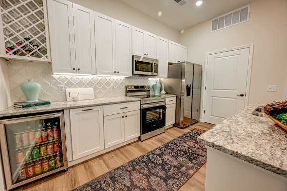 A kitchen with white cabinets and a marble countertop.