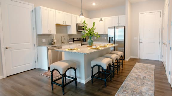 a kitchen with white cabinets and a large island with a granite countertop