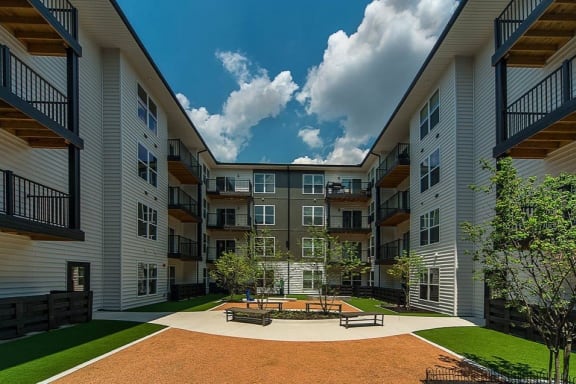 a courtyard with a firepit and benches in the middle of an apartment complex