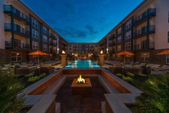 a courtyard with a pool and firepit at night