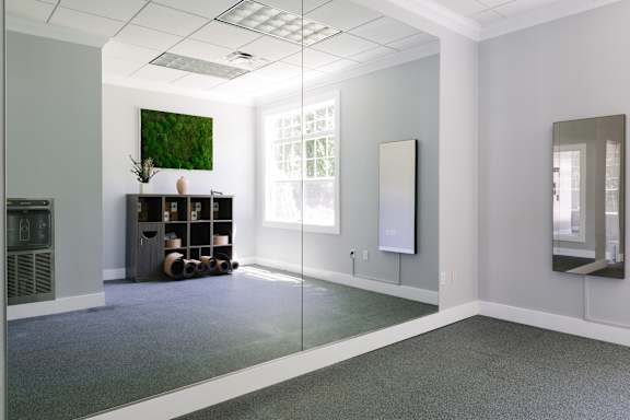 A room with a large mirror on the wall and a green rug on the floor.