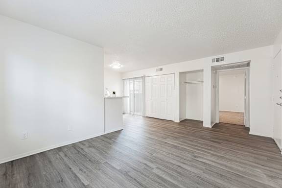A spacious room with wooden flooring and white walls.