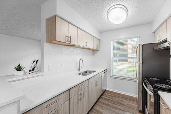 A kitchen with a sink, cabinets, and a window.