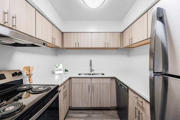 A kitchen with a stove, sink, and refrigerator.