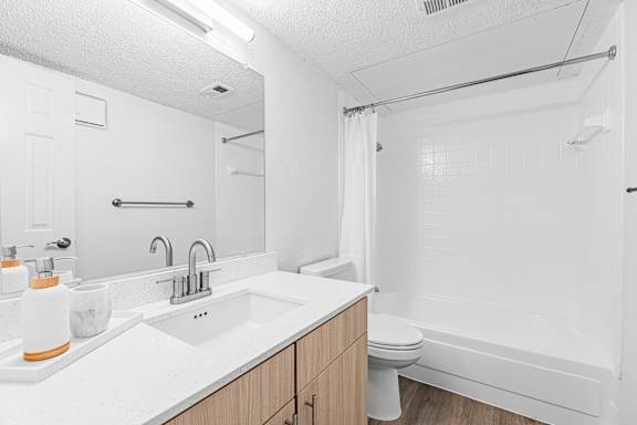 A white bathroom with a sink, toilet, and shower.