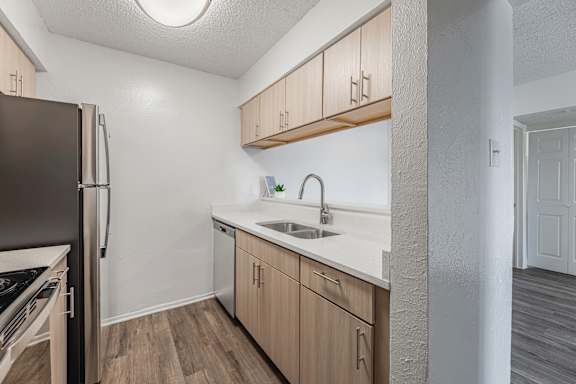 A kitchen with a black refrigerator, wooden cabinets, and a white countertop.
