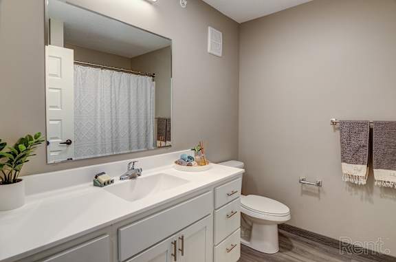 A bathroom with a white sink, toilet, and a mirror.