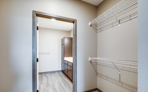 A white closet with a mirror and shelves.