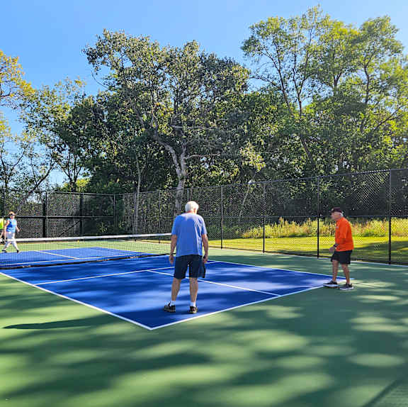 Two men are playing tennis on a blue court.