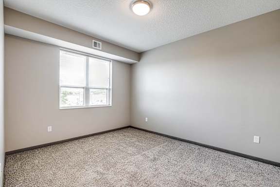 an empty room with a window and carpeting