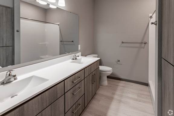 A bathroom with a white sink, mirror, and toilet.