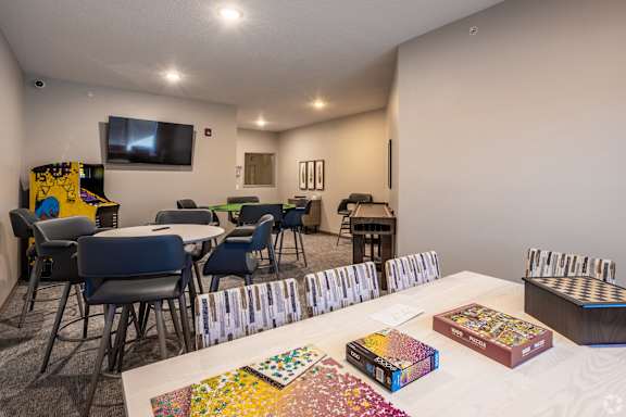 A room with a white table and chairs, a television, and a collection of jigsaw puzzles.