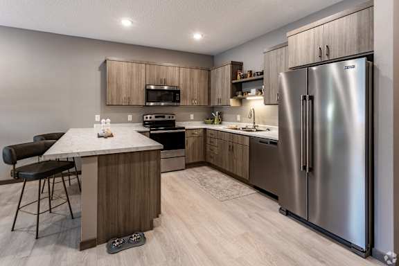 A modern kitchen with a refrigerator, stove, and sink.