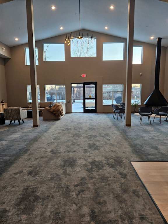 A large room with a grey carpet and a chandelier hanging from the ceiling.
