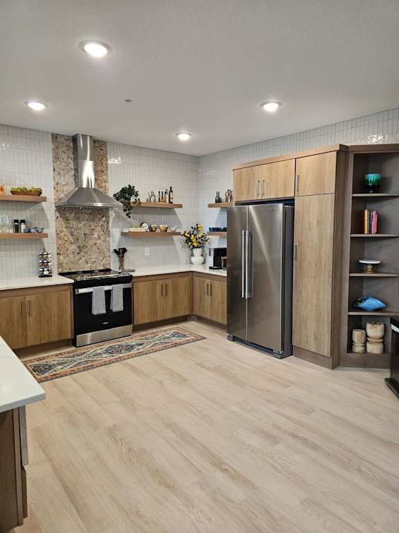 A modern kitchen with wooden cabinets and a stainless steel refrigerator.