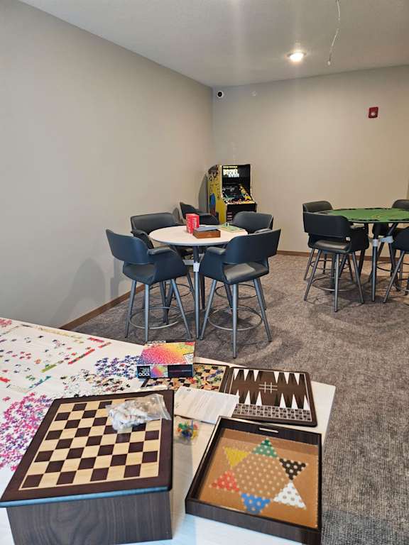 A room with a table, chairs, and a checkerboard on the table.
