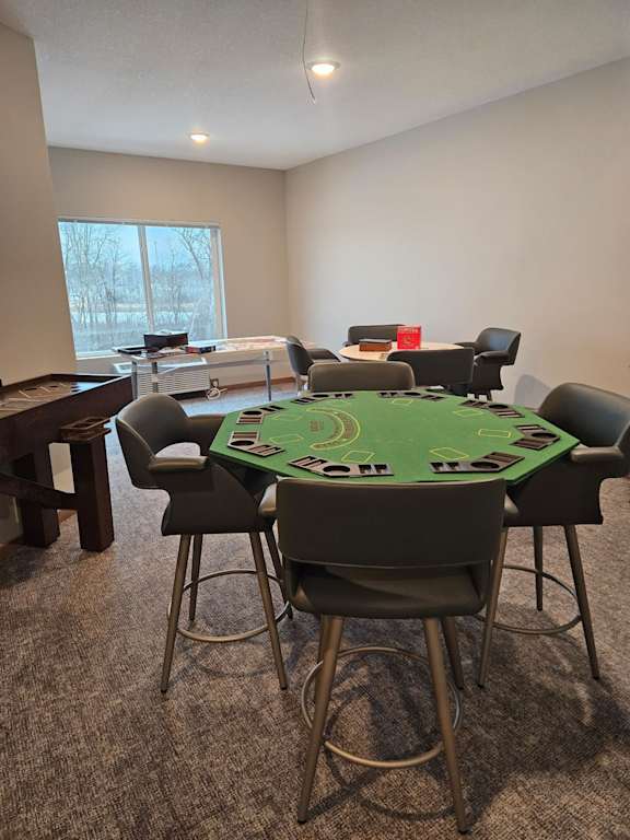 A poker table surrounded by chairs in a room.
