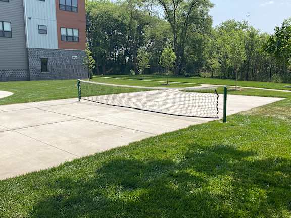 A tennis court with a net and green grass.