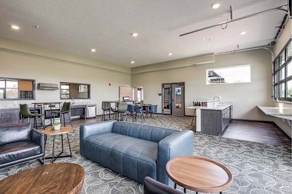 A spacious room with a blue couch, a wooden table, and a patterned carpet.