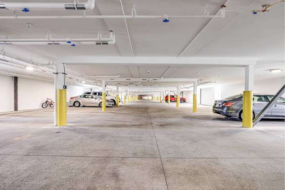 A parking garage with cars parked and yellow poles.