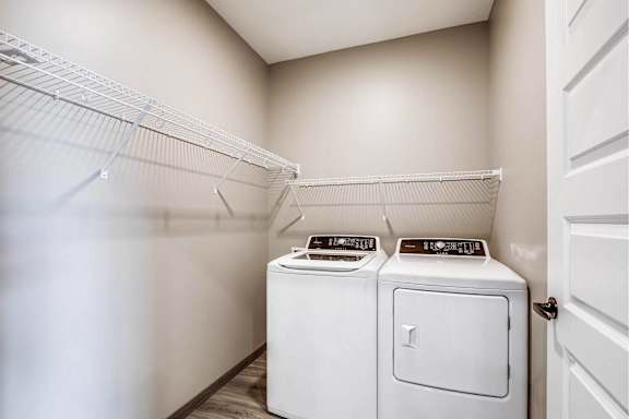 A laundry room with two washing machines and a shelf.
