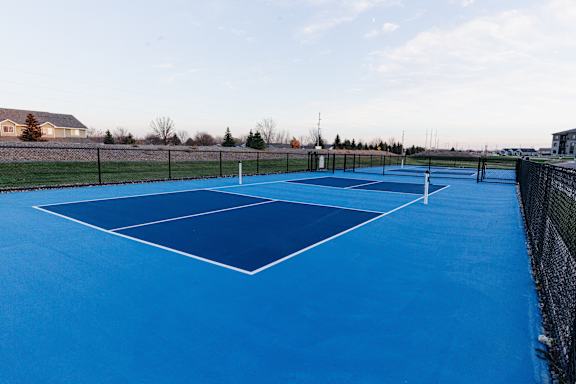a tennis court with blue surface on a sunny day