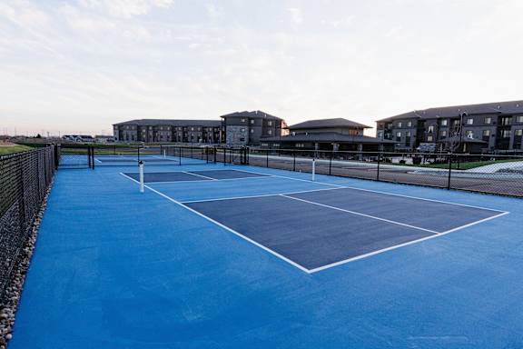 a tennis court with apartments in the background