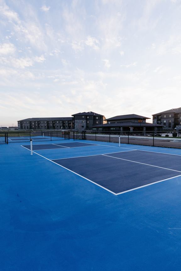 a blue tennis court with buildings in the background
