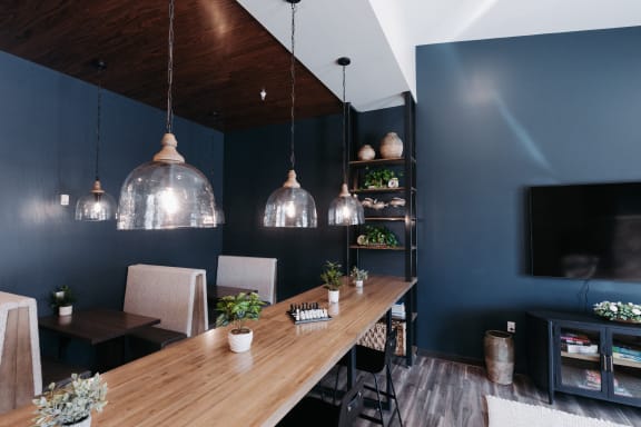 a dining room with blue walls and a long wooden table and glass lights