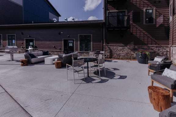 an outdoor patio with chairs and tables and a building in the background
