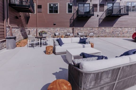 a patio with couches and a table and chairs in front of a house