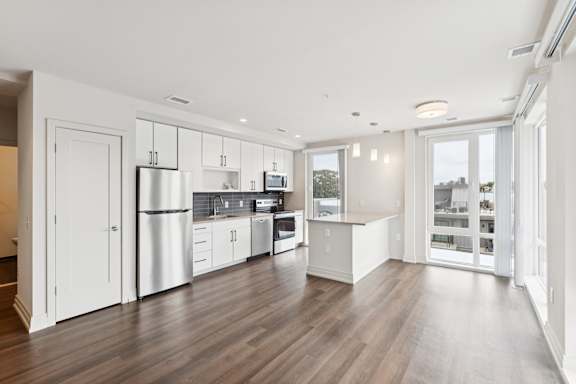 A kitchen with white cabinets and a wooden floor.