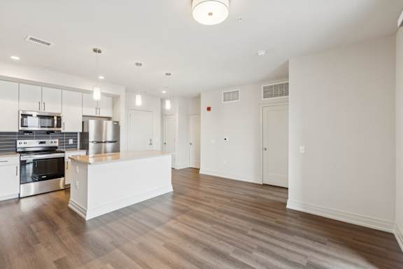 A spacious kitchen with a stainless steel refrigerator and oven, and a white island in the middle.