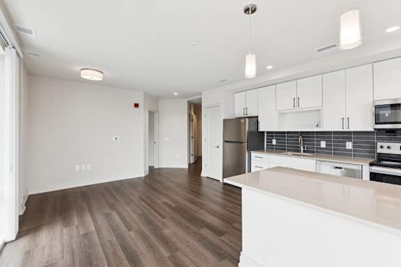 A kitchen with white cabinets and a wooden floor.