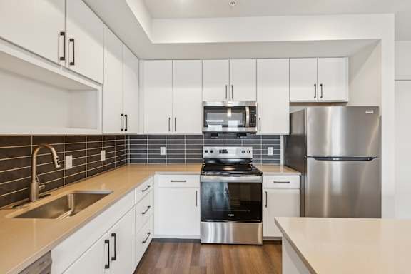 A modern kitchen with white cabinets and stainless steel appliances.