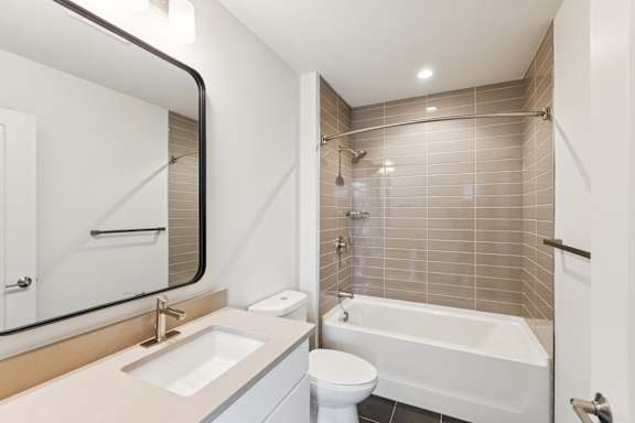 A white toilet sits next to a white bathtub in a bathroom.