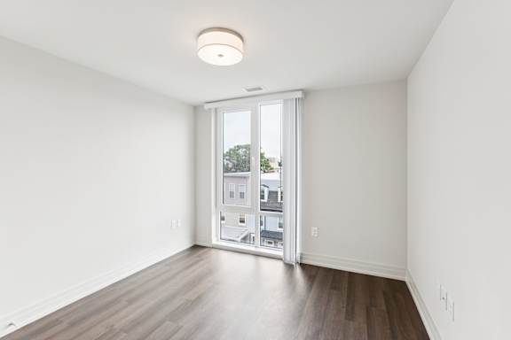 A room with a sliding glass door leading to a balcony.