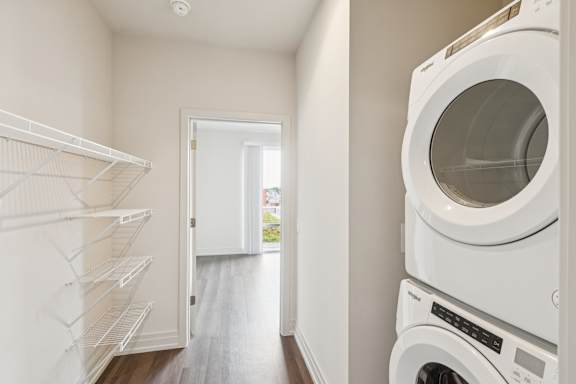 A white washing machine sits in a laundry room with a doorway leading to a hallway.