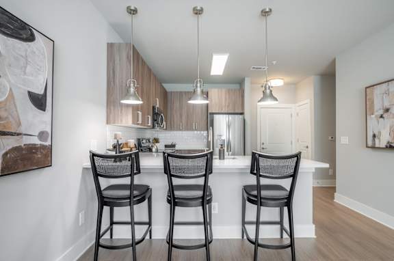 A kitchen with a bar area and chairs.at The Delaney at East Park Apartments, Kennesaw, 30144