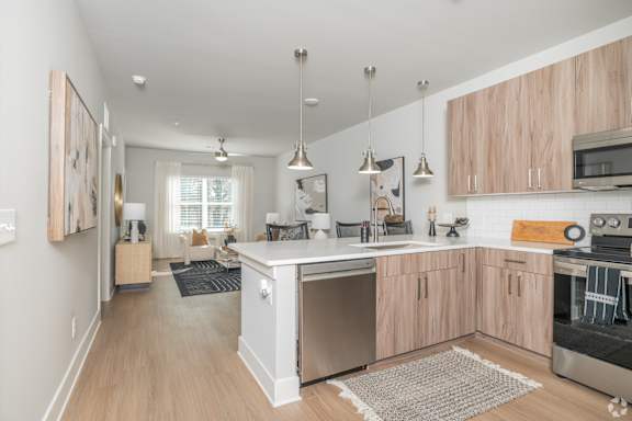 A modern kitchen with wooden cabinets and stainless steel appliances.at The Delaney at East Park Apartments, Kennesaw, 30144