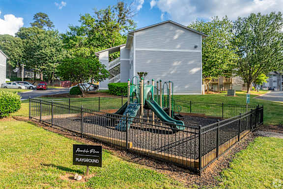 A playground with a green slide and a sign that says "Barnes Park PLAYGROUND".