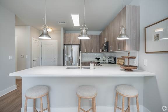 A modern kitchen with a white island and bar stools.at The Delaney at East Park Apartments, Kennesaw, GA