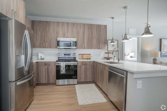 Floor Plan  A modern kitchen with wooden cabinets and stainless steel appliances.at The Delaney at East Park Apartments, Kennesaw