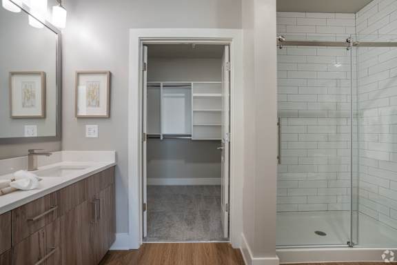 A bathroom with a walk-in shower and a sink.at The Delaney at East Park Apartments, Georgia