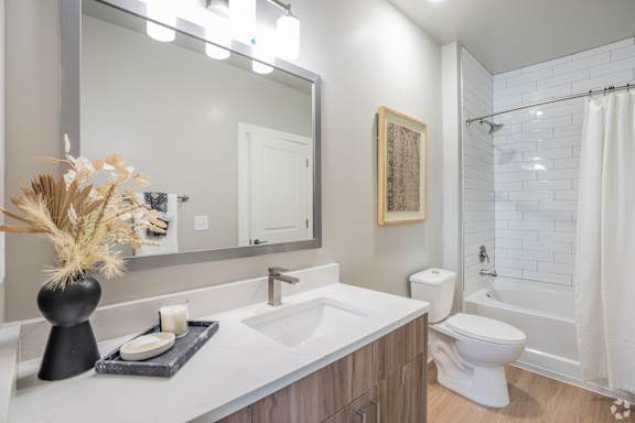 A bathroom with a white toilet and a white shower curtain.at The Delaney at East Park Apartments, Kennesaw, 30144