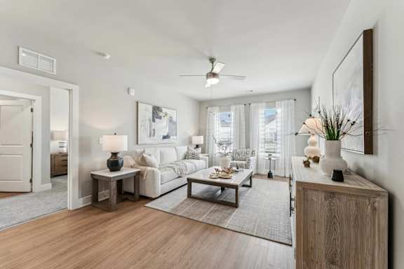 A living room with a white couch, a wooden side table, and a large painting on the wall.