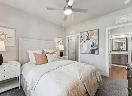 A bedroom with a large bed, a ceiling fan, and a dresser.